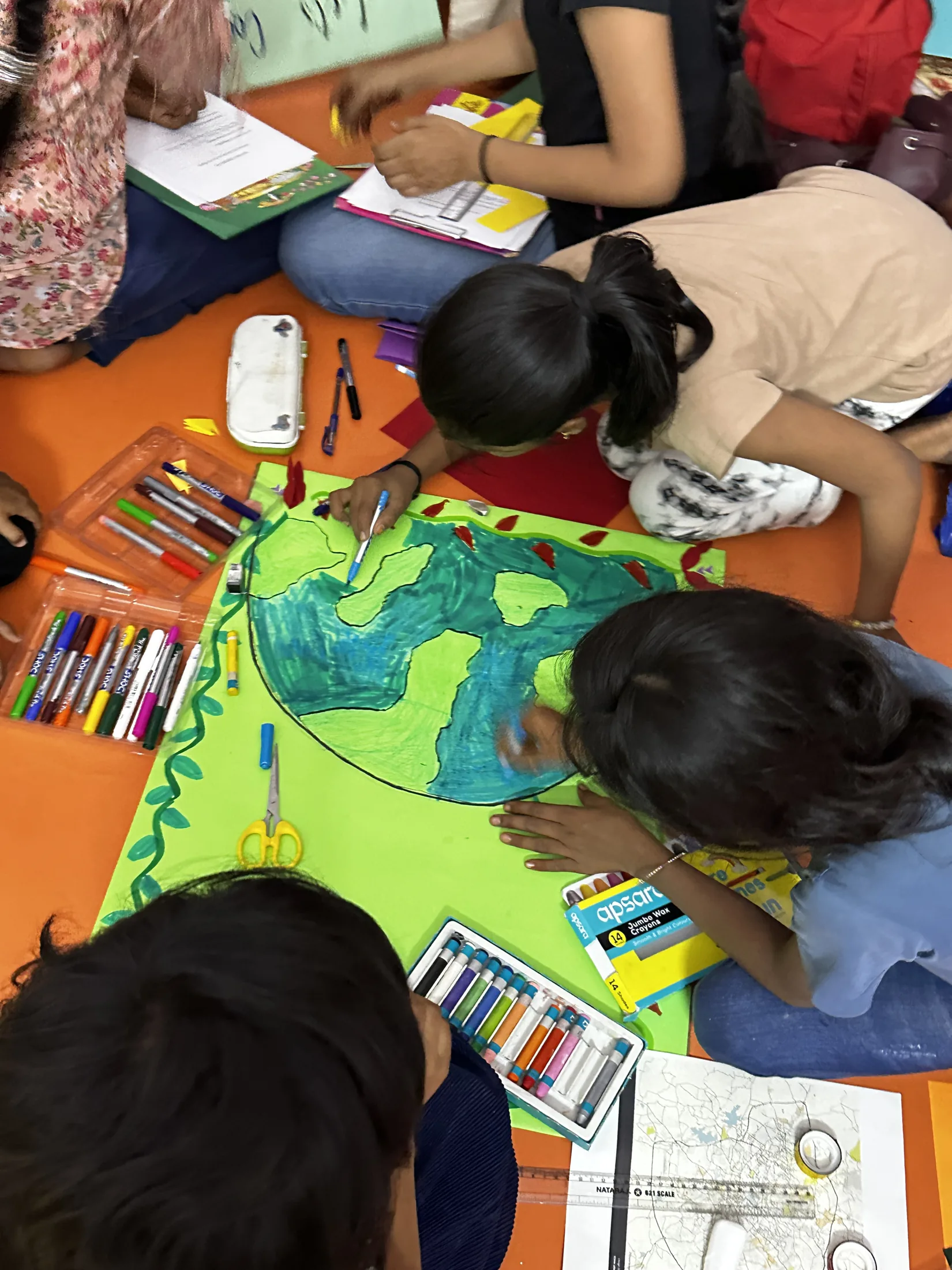 A closer view of children drawing a large city-cooling poster together.