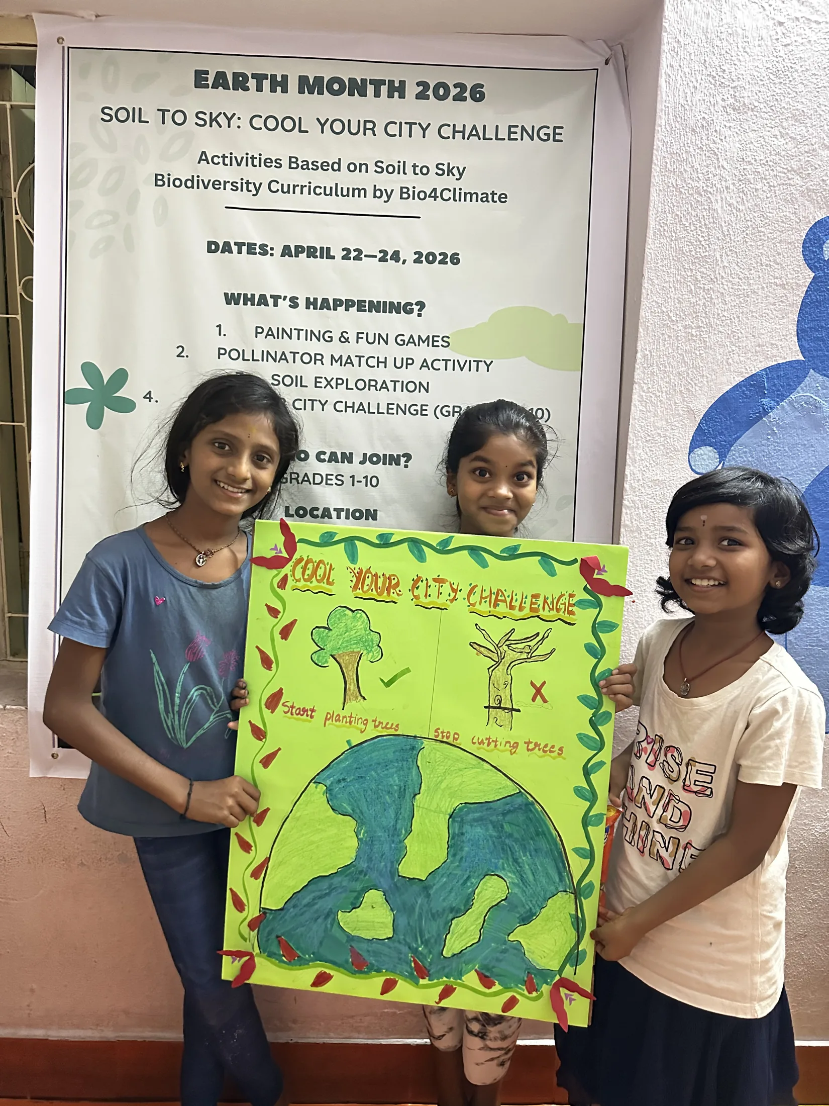 Three girls from a local school present a poster calling for planting trees and stopping tree cutting.