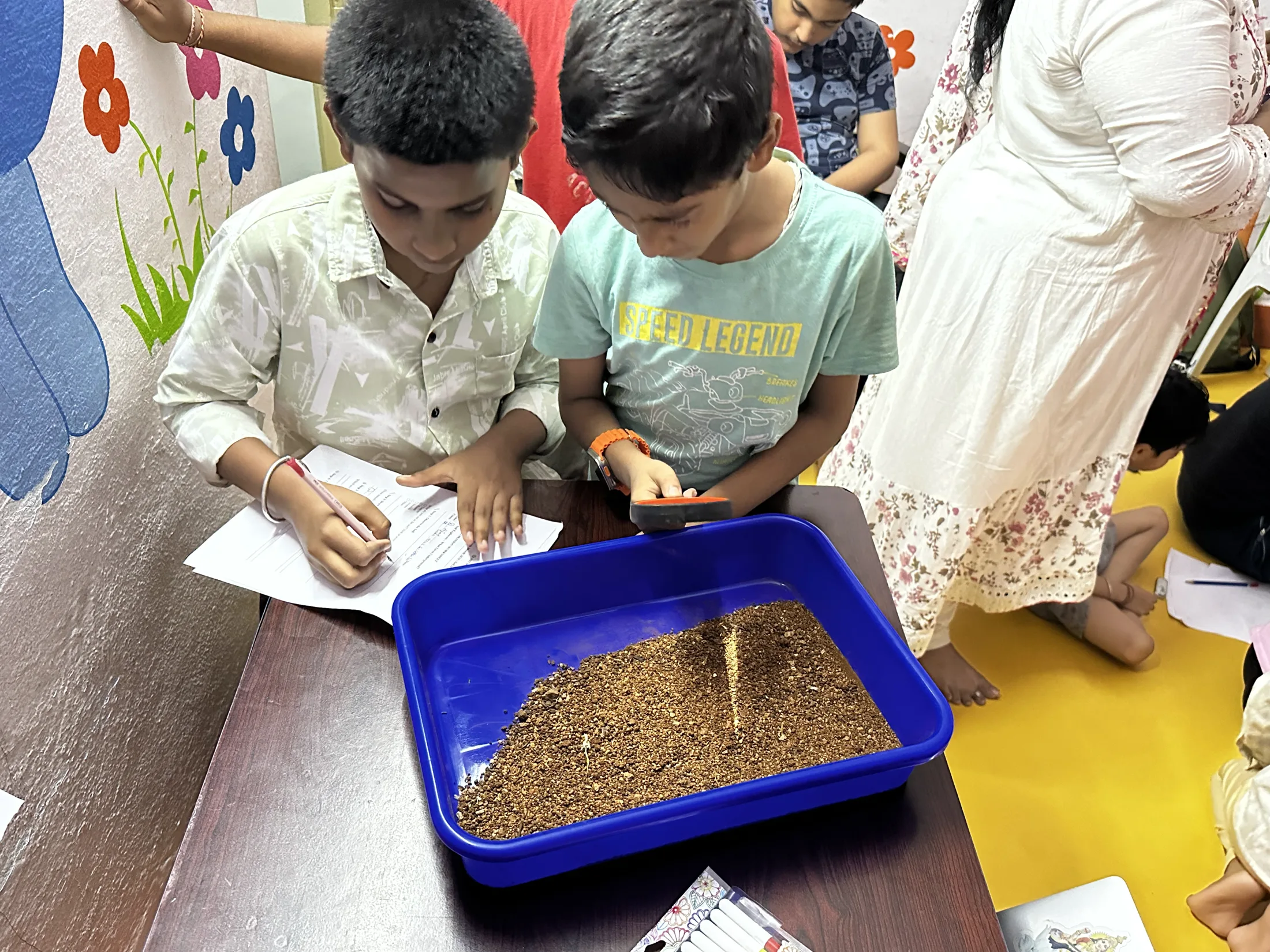A small group of children studies soil samples together at close range.